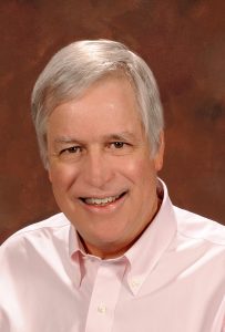 Man with white hair and pink shirt