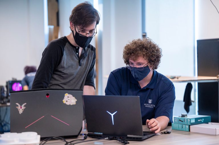 two masked people using computers