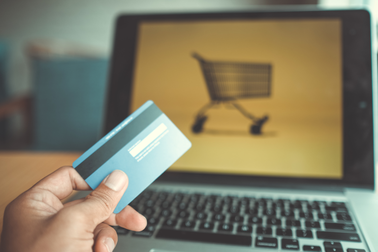 hand holding credit card; laptop in the background