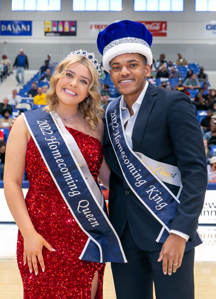 a man and a woman, both wearing Homecoming sashes