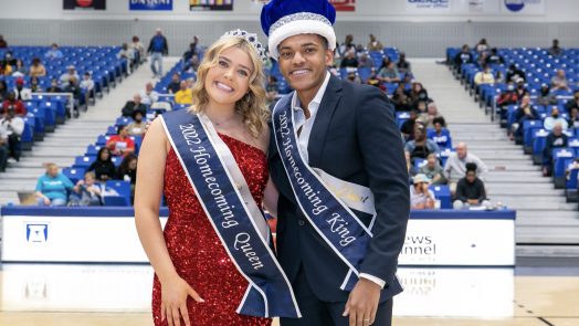 a man and a woman, both wearing Homecoming sashes