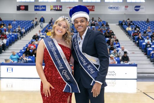 a man and a woman, both wearing Homecoming sashes