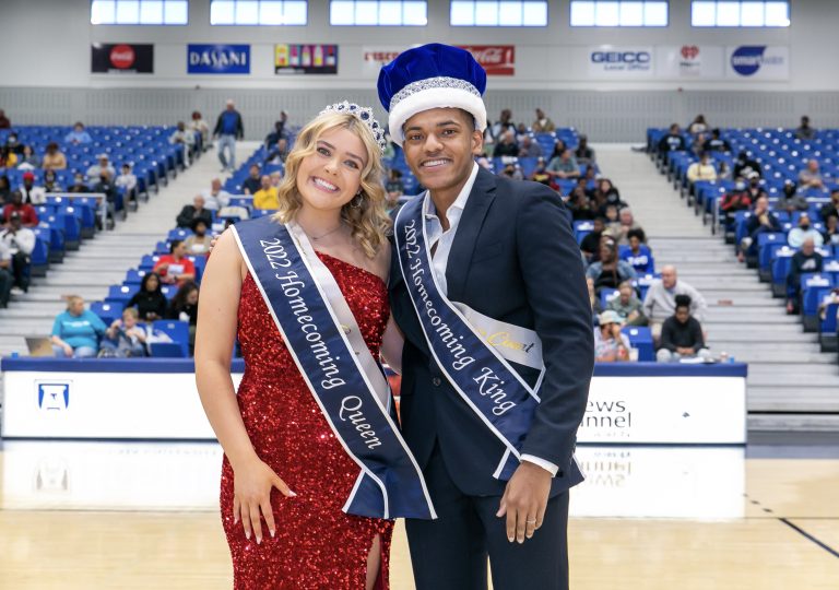 a man and a woman, both wearing Homecoming sashes