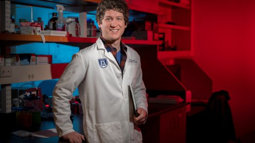 Curly haired man in white lab coat