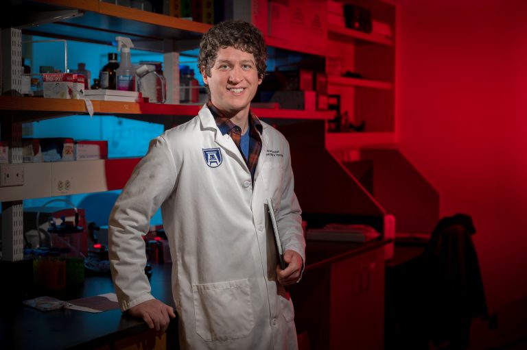 Curly haired man in white lab coat