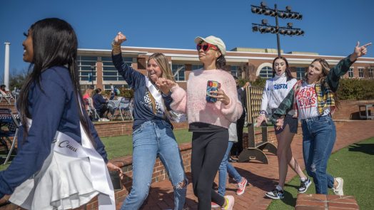 Five students walking with hands in air