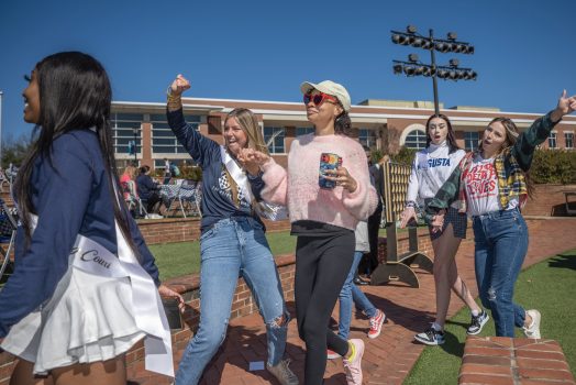 Five students walking with hands in air