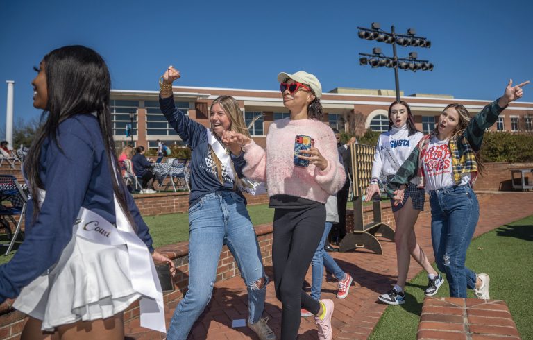 Five students walking with hands in air
