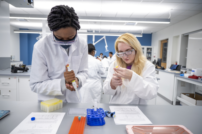 two women in white coats doing science