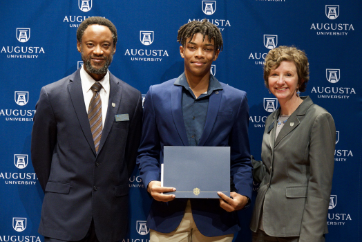 male student standing beside a man and a woman