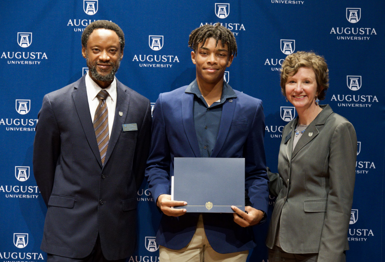 male student standing beside a man and a woman