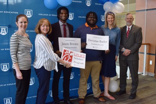 Five men and women with a giant check