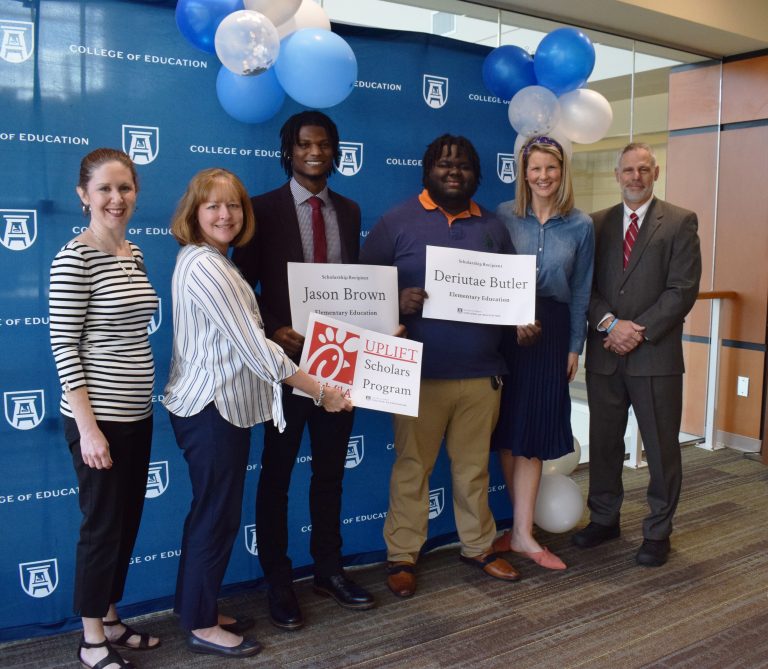Five men and women with a giant check