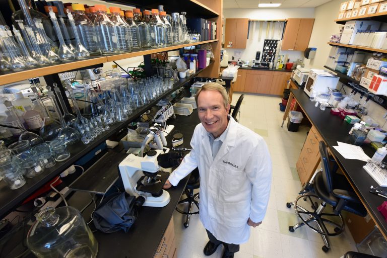 man in white coat standing in lab