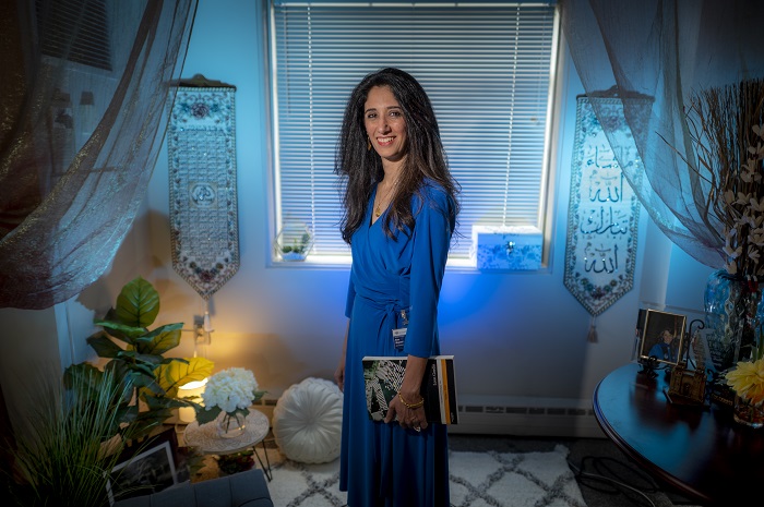 woman stands in front of window of office holding book