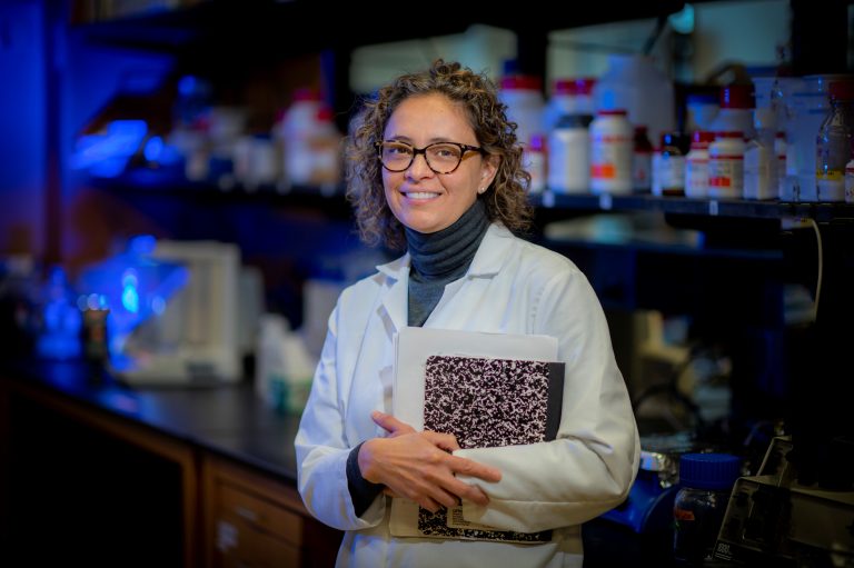 Woman with curly hair in white lab coat