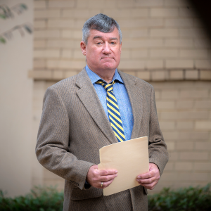 man standing in front of wall with folder