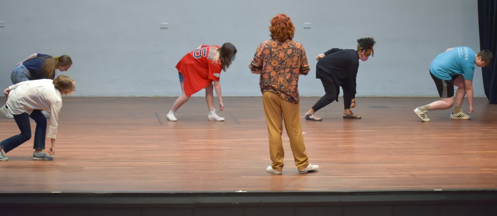 man standing in front of dancers on stage