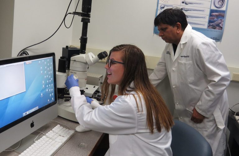 woman and man look at a computer in a lab