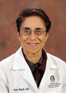 woman doctor with short hair and glasses in front of a backdrop