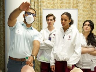 man and students learning in medical environment