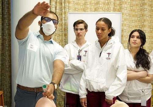 man and students learning in medical environment