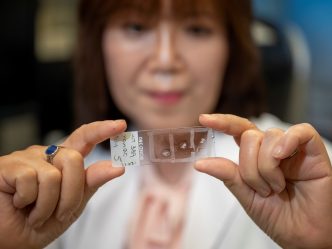 Woman holds microscope slide in foreground