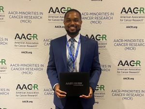 man smiling while holding folder in front of backdrop