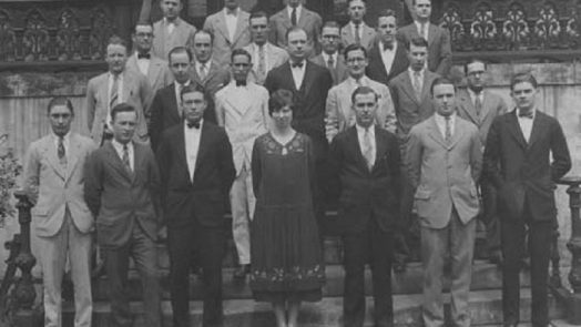 one woman stands for class photo with group of men