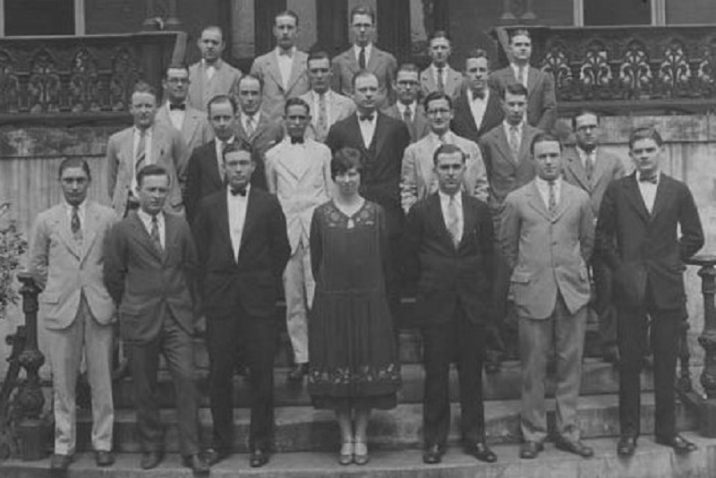 one woman stands for class photo with group of men