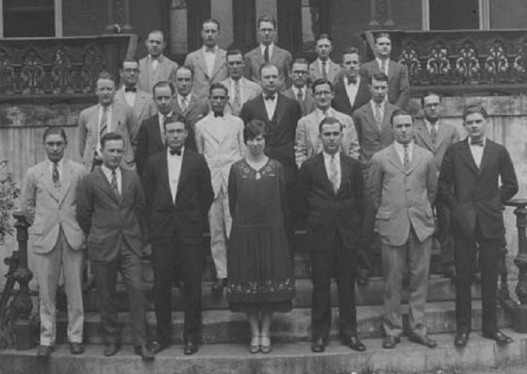 one woman stands for class photo with group of men
