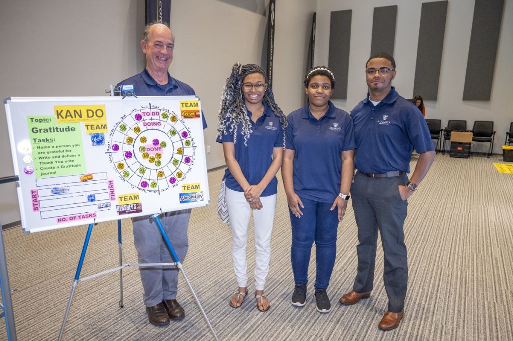 Students and teacher stand in front of poster