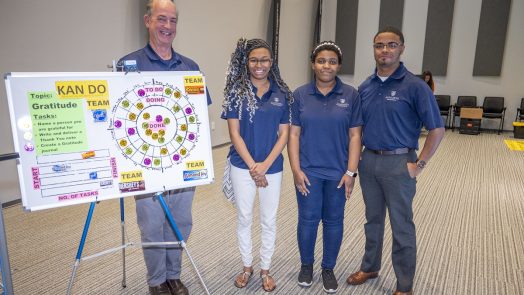 Students and teacher stand in front of poster