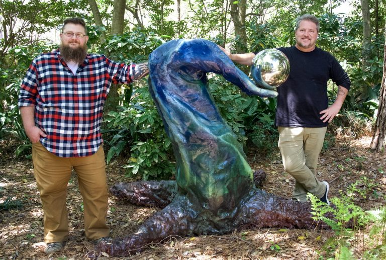 two people standing by sculpture