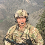 soldier smiling in front of a mountain range