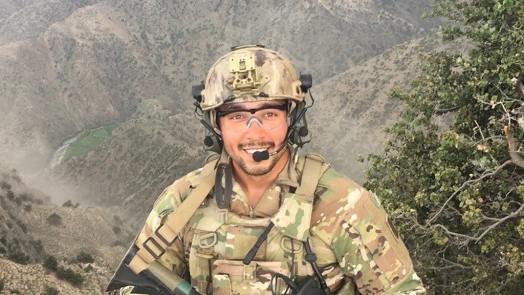 soldier smiling in front of a mountain range
