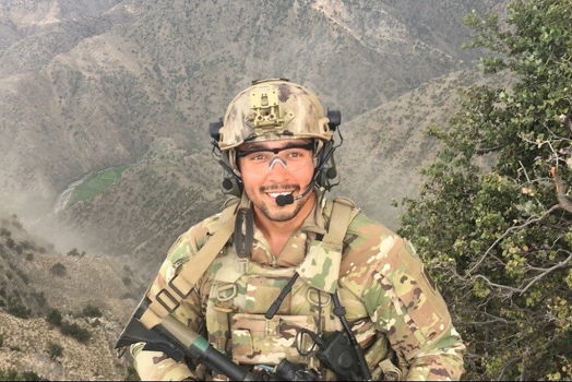 soldier smiling in front of a mountain range