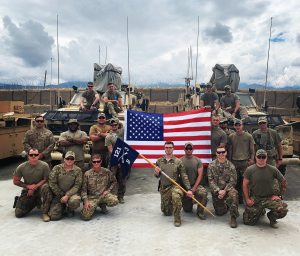 soldiers stand outside in front of American Flag