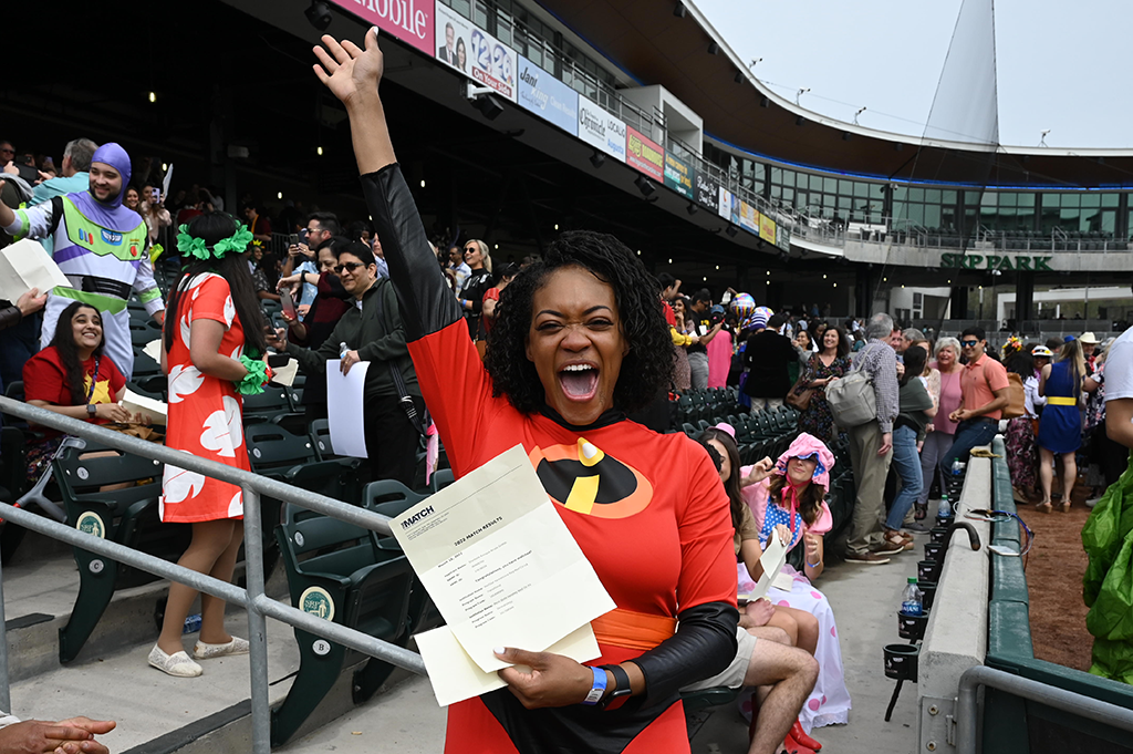 woman in superhero uniform cheering in crowded stadium
