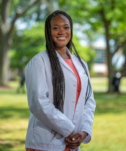 woman in white lab coat standing outside smiling
