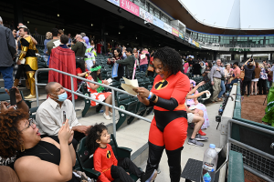 woman dressed as a superhero reads a letter with family looking on