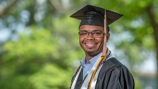 man in glasses wearing graduation regalia