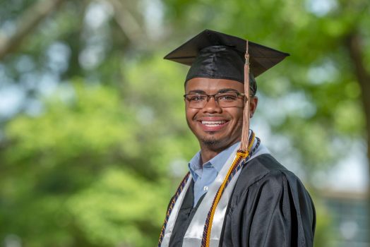 man in glasses wearing graduation regalia
