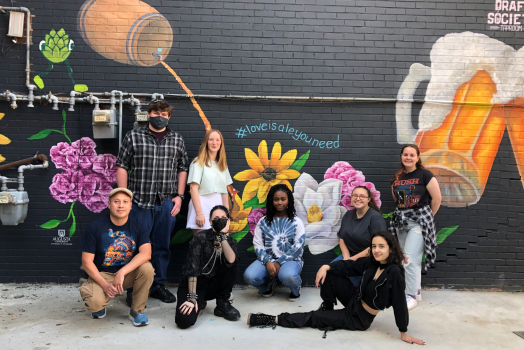 Group of men and women standing in front of a mural