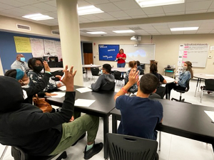 students raise their hands in a classroom