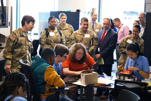 group of adults watch as children use computer