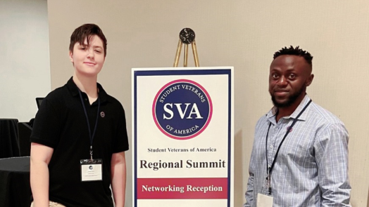 two men in front of a conference sign