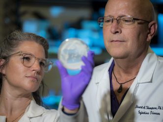 Close up of woman with glasses and man with glasses looking at petri dish