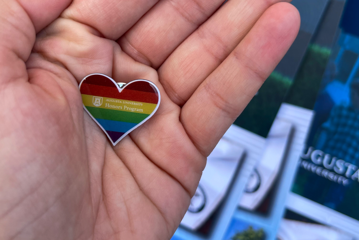 rainbow heart pin with the Augusta University Honors Program logo