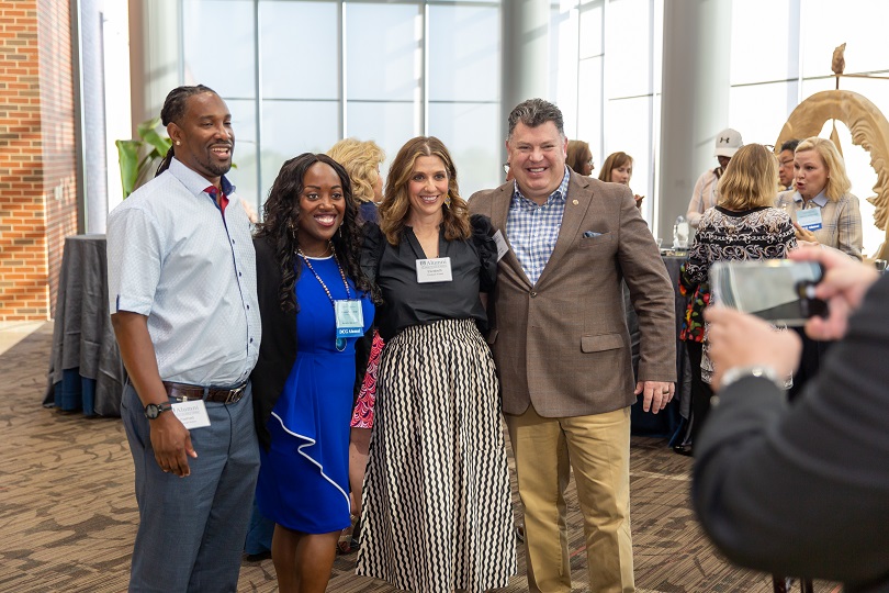 Four people smiling and posing for photo